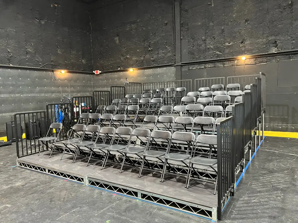 Bleacher and Riser Rental — Tiered bleacher with folding chairs and perimeter railings — black-box theater seating bank