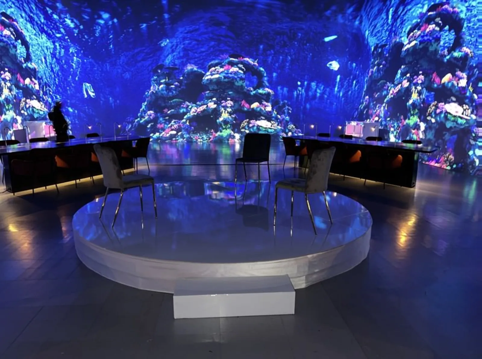 Round riser with curved LED wall, panel chairs, and dinner audience layout