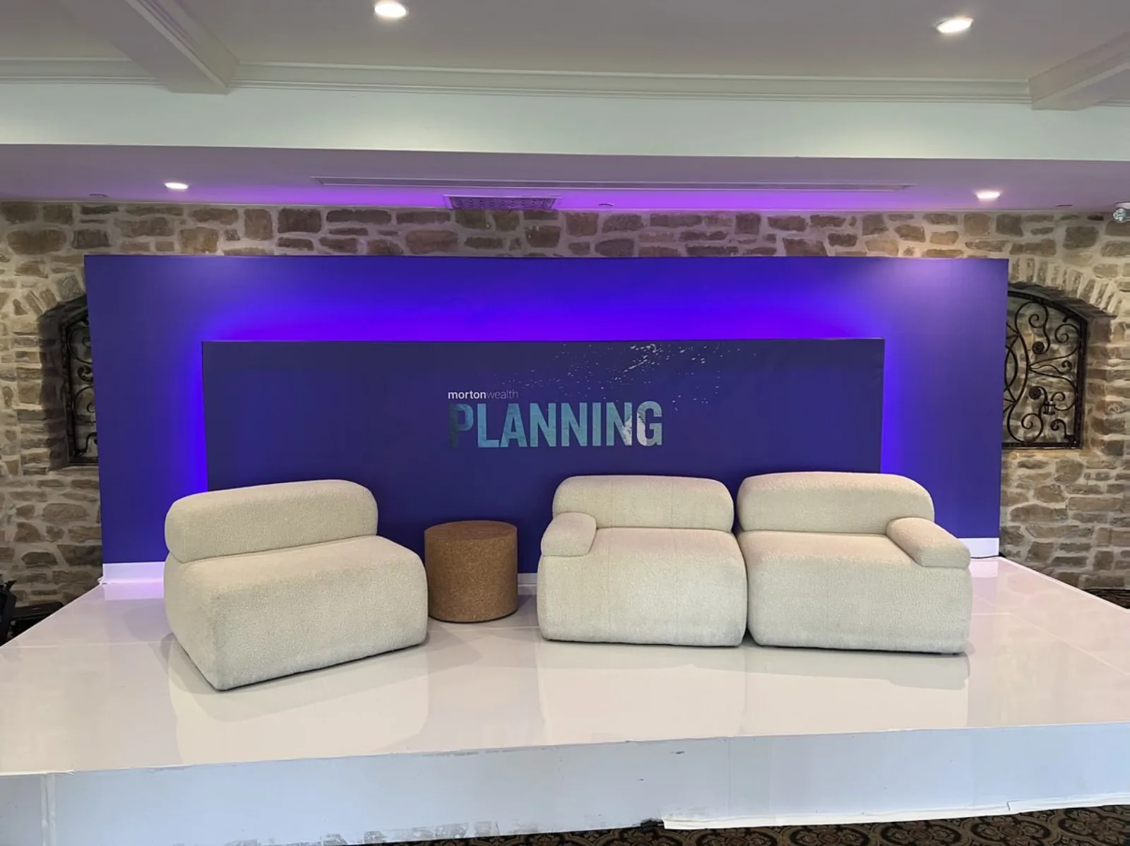Wealth-management symposium stage with three sofa seats and podium offstage