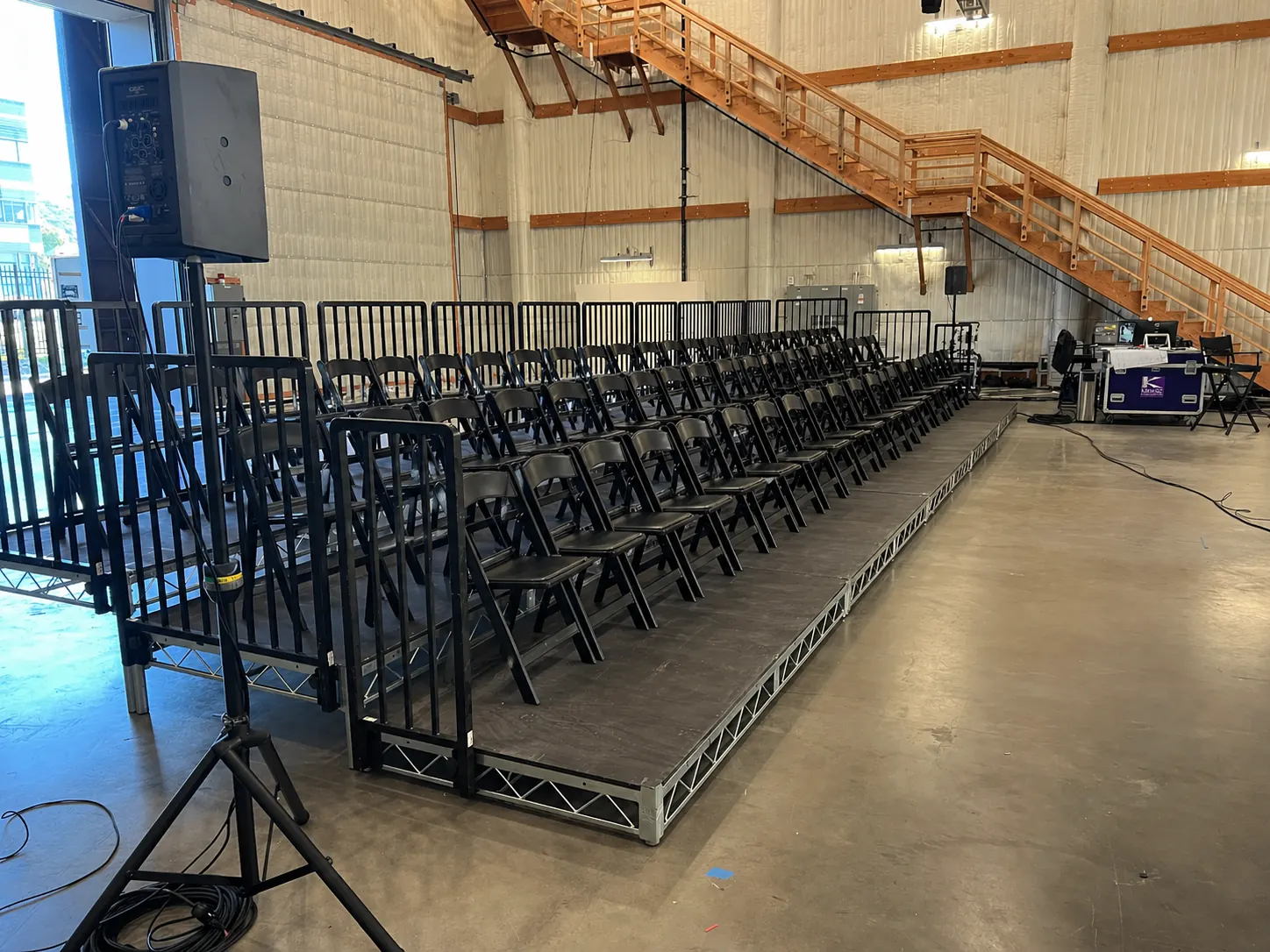 Bleacher and Riser Rental — Long riser platform with rows of folding chairs and side railings — warehouse audience build