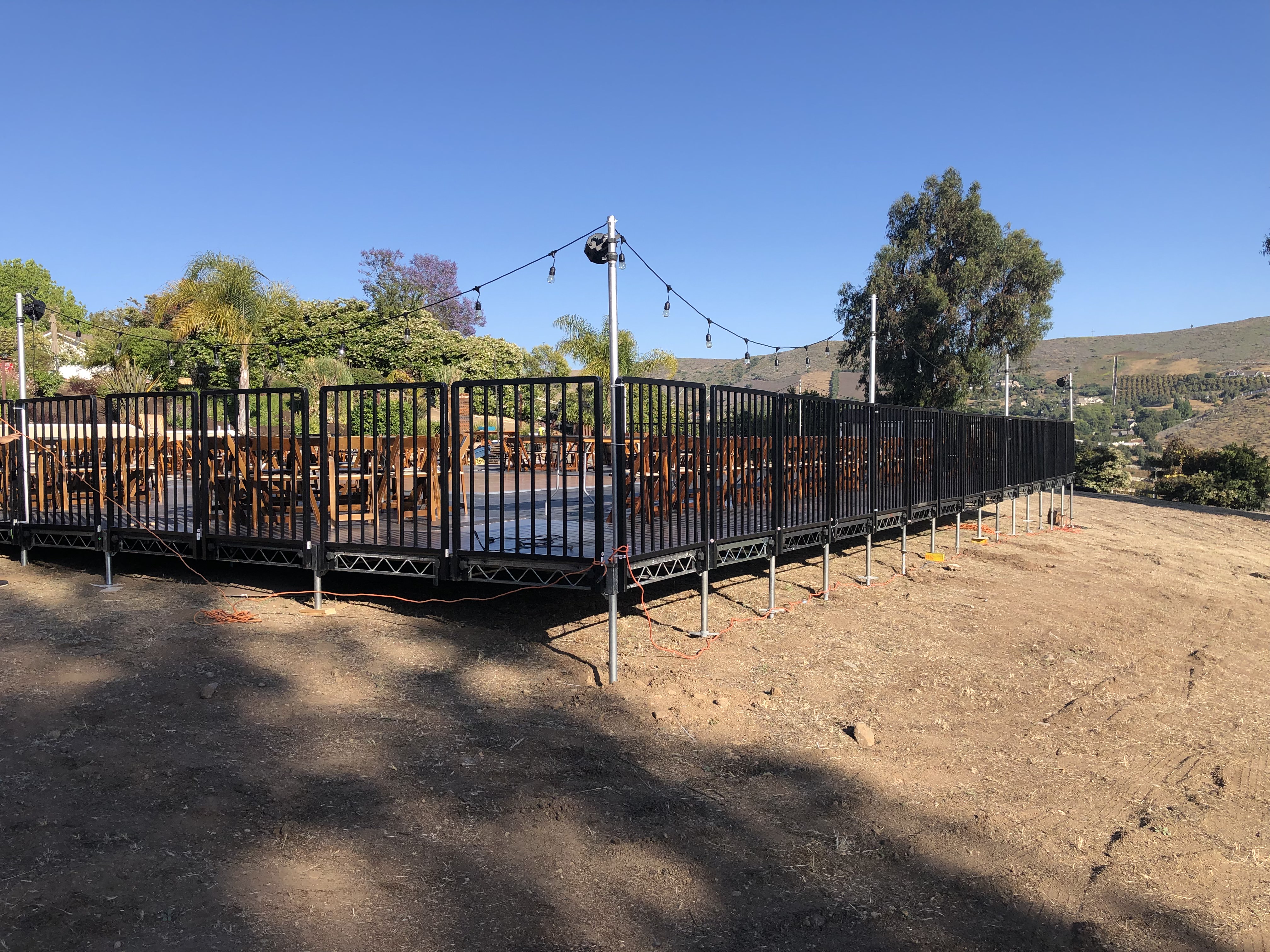 Temporary Sub Floor Rental — Elevated sub-floor platform with railings on uneven hillside ground — outdoor guest seating build