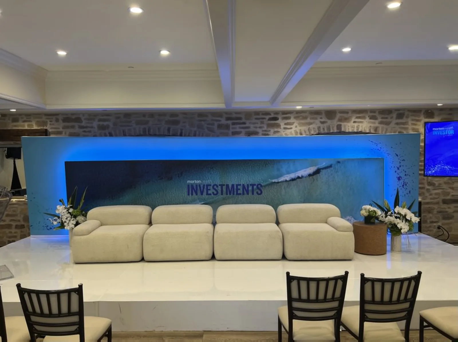 Branded panel set with sofa seats, lavalier mics, and floor TV monitor