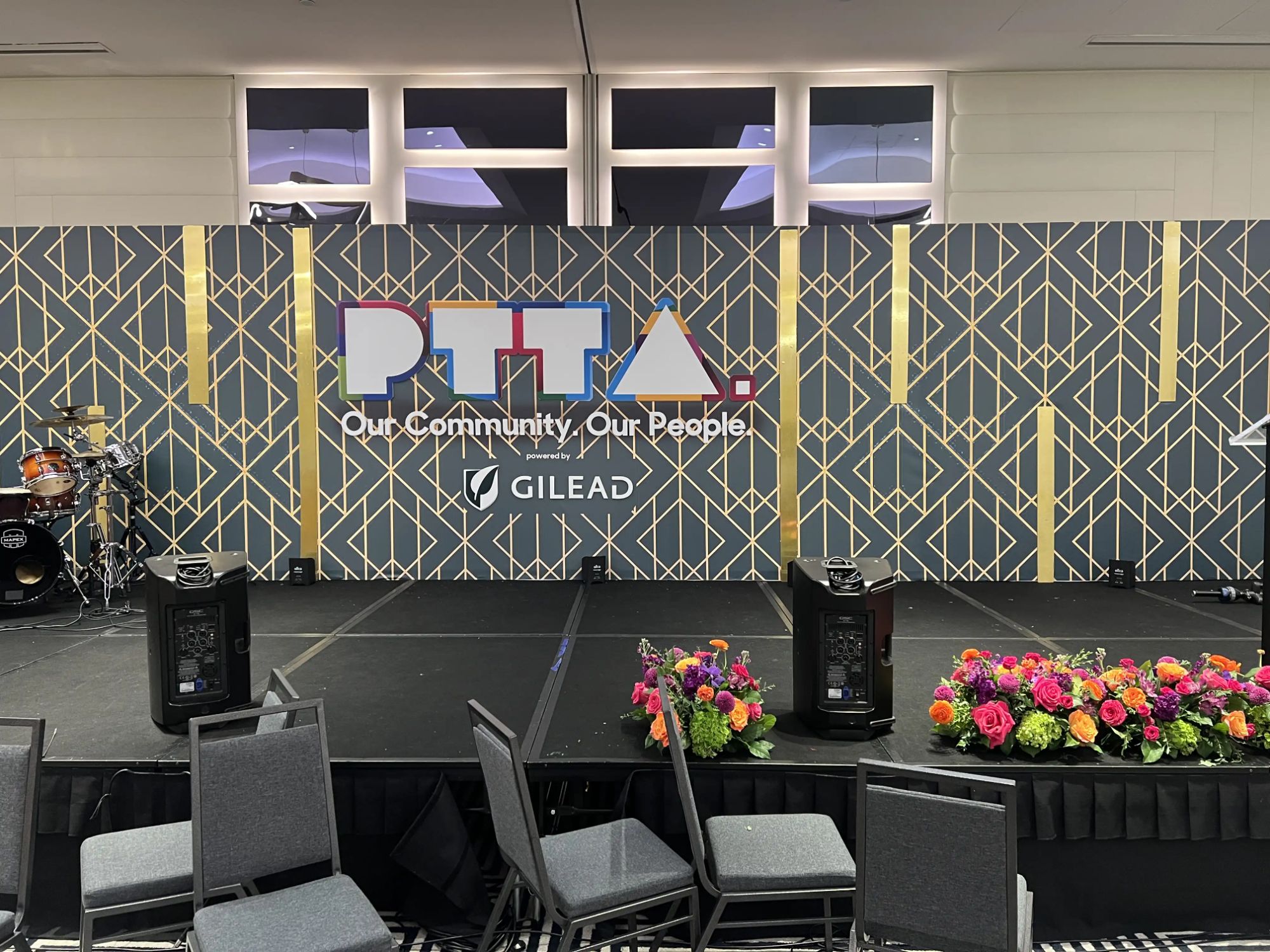 PTTA branded backdrop with custom gold geometric graphic over flat-wall set — Gilead community event