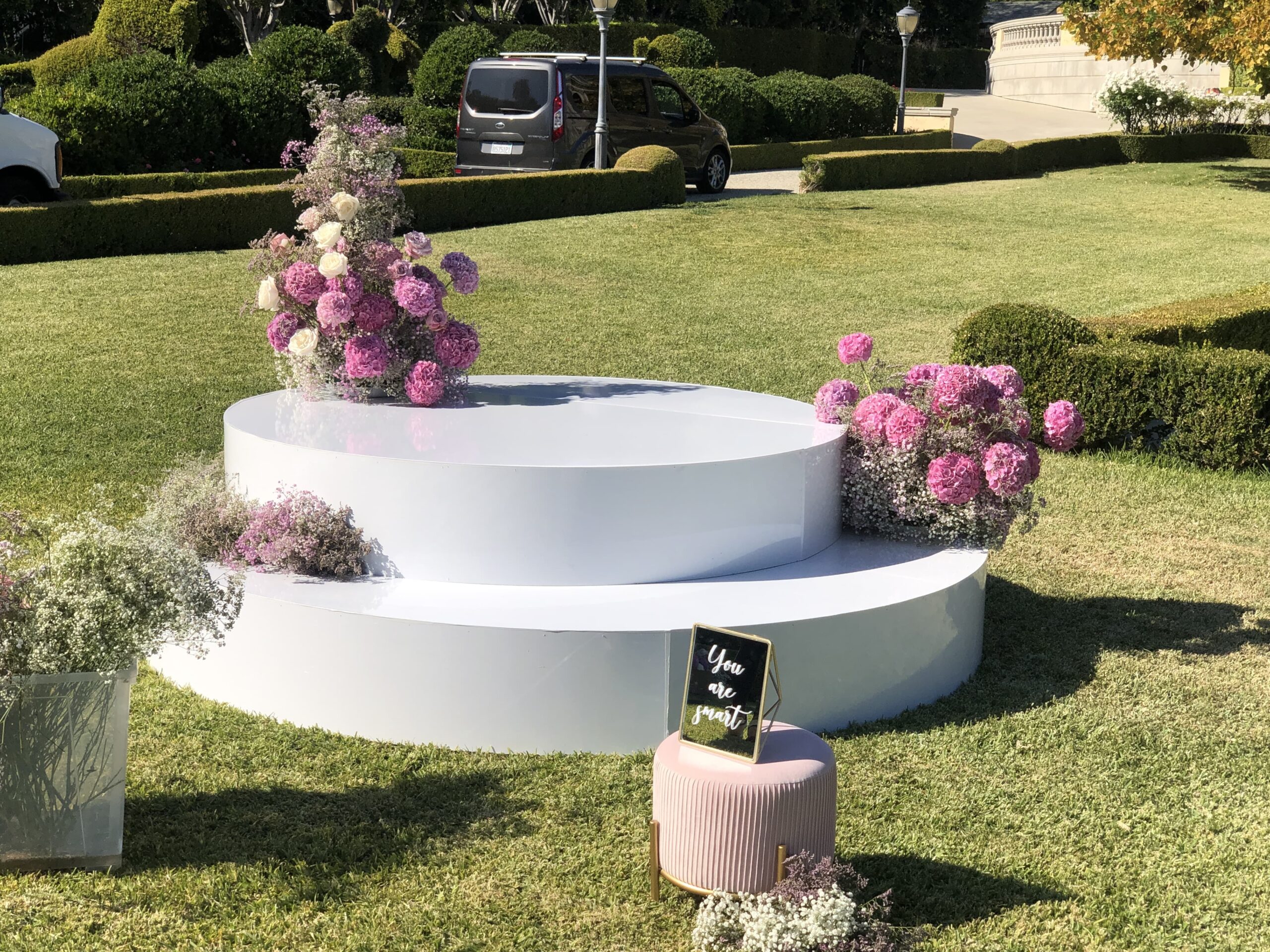 Custom round white stage rental with floral decor for outdoor event in Los Angeles